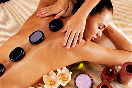 Adult woman having hot stone massage in spa salon